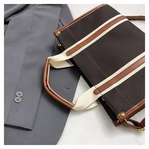 Detailed top view of large canvas tote bag in dark brown with leather trim and gold rivets