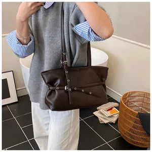 Détail du sac cabas en cuir marron foncé avec sangles à boucles et œillets argentés