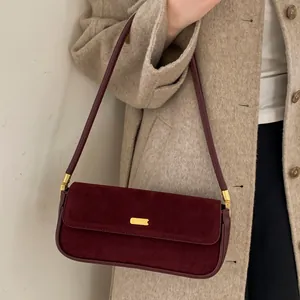 Sac baguette minimaliste en daim bordeaux avec boucle en métal doré sur modèle