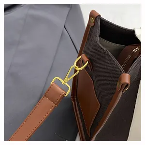 Close-up of golden metal hooks and brown leather details on a vintage canvas tote bag