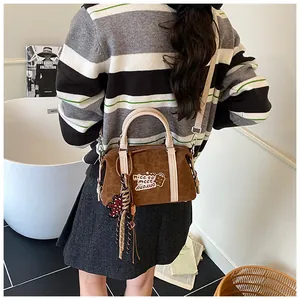 Brown vintage suede Boston bag with bear graphic and charms shown on a model