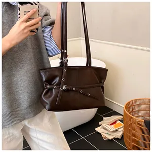 Détail d'un sac cabas en cuir marron foncé avec ceinture élégante et œillets en métal