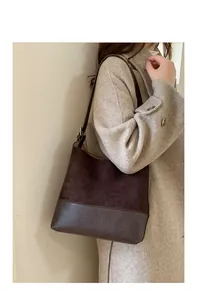 Detail of vintage dark brown patchwork tote bag worn by a model in a minimalist style