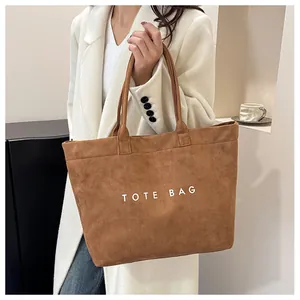 Sac fourre-tout en daim marron avec texte blanc porté par un mannequin pour un look urbain