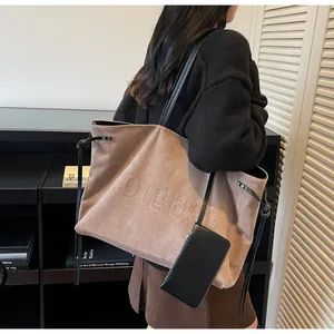 Détail du sac cabas en daim kaki avec gaufrage TOTE BAG et petite pochette noire sur modèle