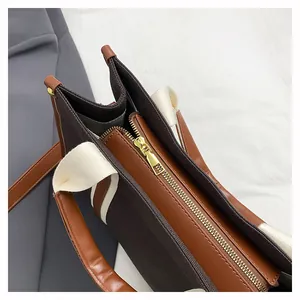 Close-up of brown canvas tote with premium leather trim and gold metal zipper closure