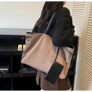 Détail du sac cabas en daim marron avec texte embossé et pochette en cuir noir