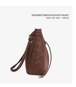 Close-up of vintage brown suede shoulder bag with textured finish and knotted strap detail