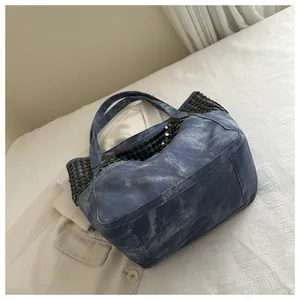 Λεπτομερής όψη vintage τσάντας από ξεπλυμένο μπλε denim με μαύρα μεταλλικά τρουκς διακόσμηση