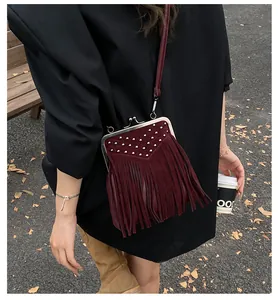 Detail of burgundy fringe crossbody bag with silver rivet V-pattern and suede texture