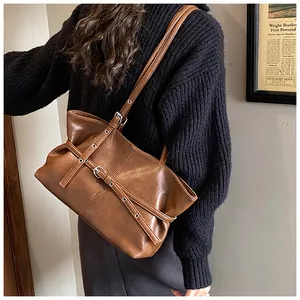 Détail du sac cabas vintage marron avec plusieurs sangles à boucles et œillets en métal