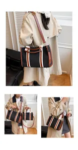 Detail view of a large canvas tote bag with leather trim and adjustable shoulder strap