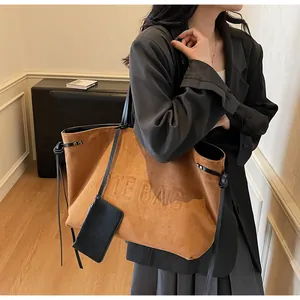Détail du grand sac cabas en daim marron avec lettrage embossé et petite pochette