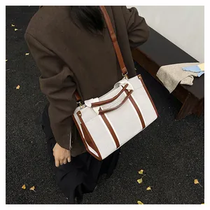 Close-up of canvas tote bag with brown leather trim and golden metal hardware details