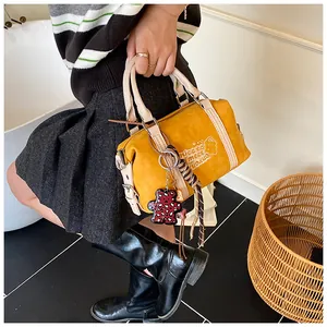 Detail of yellow retro Boston bag with bear print and decorative woven charms on a model