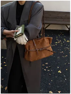 Détail d'un sac cabas en daim caramel avec fines bandoulières et boucle décorative