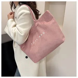 Détail de la texture d'un sac cabas en velours rose avec imprimé TOTE BAG blanc