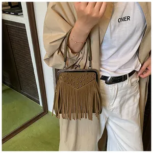 Detail of bohemian tan fringe handbag featuring vintage rivets and metal clasp closure