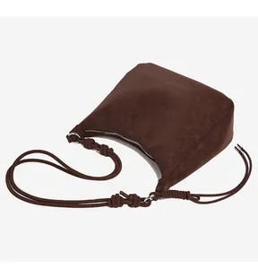Macro shot of dark brown vintage suede tote with knotted shoulder strap and silver metal rings