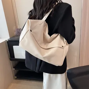 Detail of cream white tote bag with lychee grain texture and metal buckle on a model