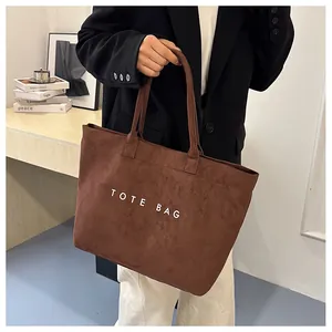 Vue détaillée du sac cabas en daim marron avec texte blanc imprimé et poignées solides