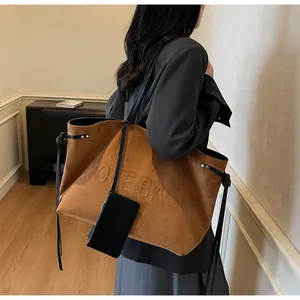 Détail du sac cabas en daim marron avec texte gaufré TOTE BAG et anses noires
