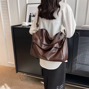 Detail of dark brown tote bag showing lychee grain leather texture and metallic rivet accents