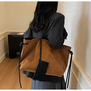 Détail du grand cabas en daim marron avec lettrage embossé et pochette noire assortie