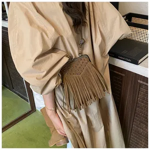 Detail of brown suede crossbody bag with long fringes and vintage metal stud accents