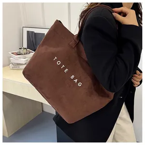 Détail du sac cabas en velours côtelé marron avec lettrage TOTE BAG blanc et texture rayée