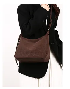 Detail of dark brown matte leather crossbody bag with decorative knotted shoulder strap