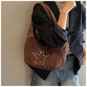 Detail of brown suede tote bag with silver star rivets shown with casual city outfit