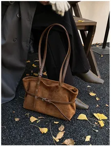 Détail d'un sac cabas en daim marron avec boucle de ceinture sur feuilles d'automne