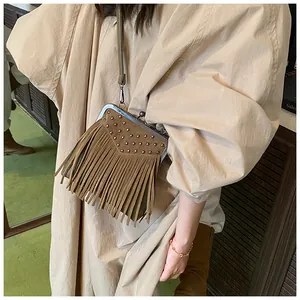 Detail view of vintage dark brown suede crossbody bag with tassels and rivets on a model