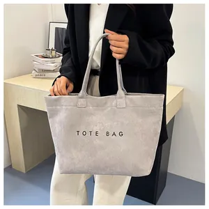 Close-up of grey suede tote bag with minimalist TOTE BAG text print and dual handles