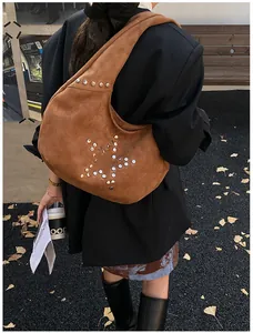 Detail of brown suede Hobo bag featuring a star pattern made of metal rivets and wide strap