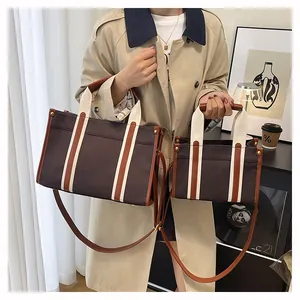 Detail view of large and small canvas tote bags with leather trim and adjustable straps