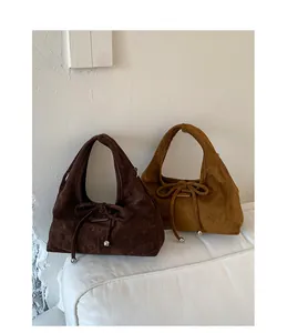 Nahaufnahme von Wildleder-Halbmondtaschen mit dekorativen Schleifen und silbernen Metallperlen