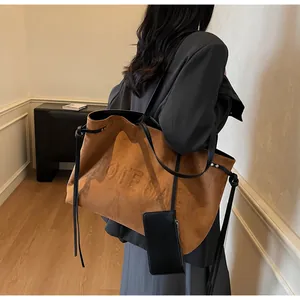 Sac fourre-tout en daim marron avec logo gaufré porté par un mannequin à l'épaule