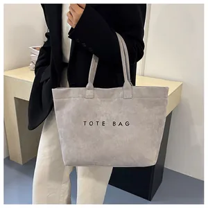 Détail d'un sac cabas en daim gris foncé avec inscription TOTE BAG noire et anses