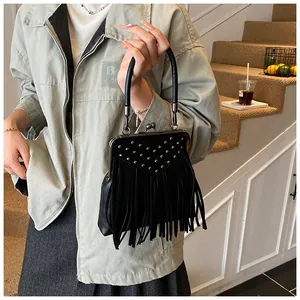 Detail of silver rivets and long fringe on black suede handbag with vintage clasp