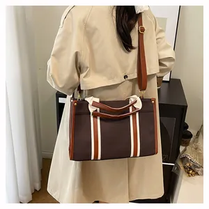 Detail of vintage canvas tote bag with brown leather trim and bicolored strap accents