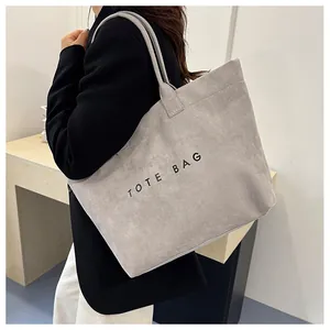 Close-up of gray tote bag in frosted texture fabric with black TOTE BAG letter print