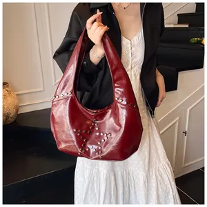Detalle de bolso hobo granate de charol con diseño de estrella en remaches plateados