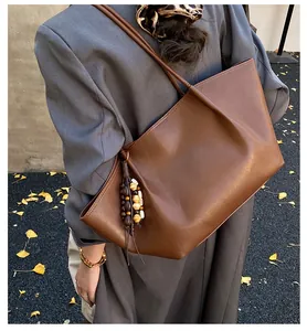 Brown vintage faux leather tote bag with wooden bead tassel shown on model shoulder