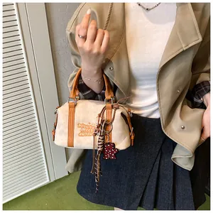 Detail of vintage beige shoulder bag featuring a bear charm and unique embroidery text