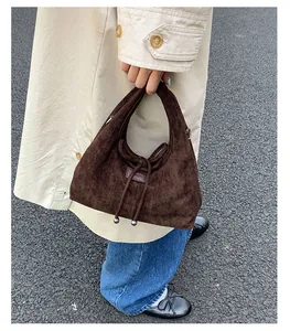 Detail der dunkelbraunen Wildlederhandtasche mit Kordelzug und Perlenverzierung am Band