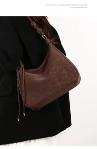 Detailed view of brown suede texture on vintage hobo bag with knotted strap and metal ring
