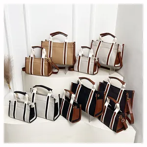 Detail showing various sizes and colors of canvas tote bags with leather trim and handles