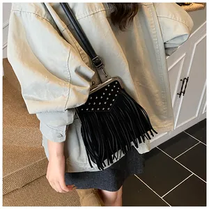 Detail view of a vintage black crossbody bag featuring metal rivets and long fringe tassels